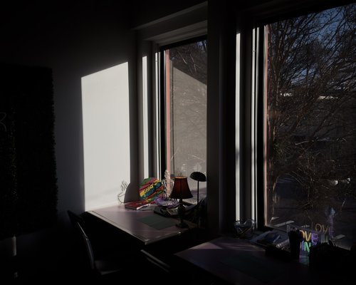 A well lit desk corner near a large window catching morning sunlight