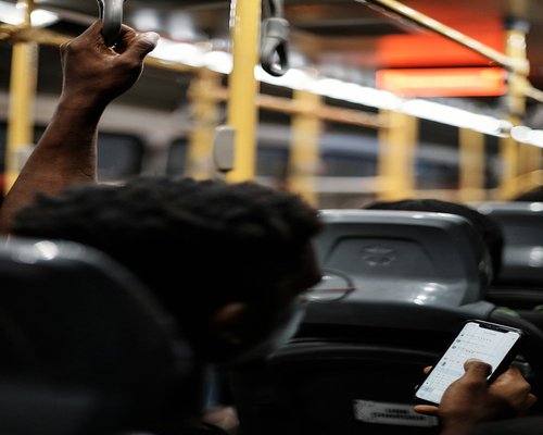 Person holding a smartphone while commuting on a bus